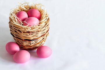 Easter composition with wicker basket and pink colored eggs