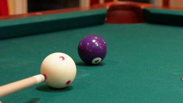 Closeup of Person Playing Pool Shooting Solid Purple 4 Ball into Corner Pocket after Practice Strokes using Cue Ball with Red Spots, Open Bridge Hand with Wooden Cue Stick and Green Felt or Cloth