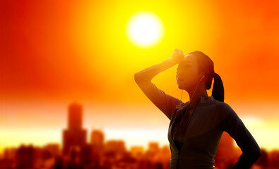 Woman shielding her eyes from sun with summer heat wave in the city background
