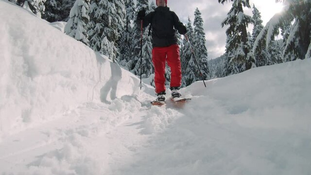 Low Angle of Man Touring Snowy Mountain Trail on Splitboard Skis and Poles