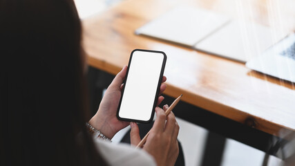 Young woman take a break and using mobile phone surfing internet at her workspace.