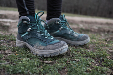 Women's trekking dirty boots in the grass and mud