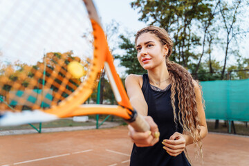 Professional tennis player doing sport on the court. She's about to hit the ball, suspended in the air, with racket. Tennis player in action. It takes a lot of energy and strength to win a match