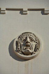 Plaster mask on wall of the theater - 410579773