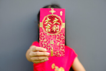 Close up  Asian  girl wearing red traditional Chinese cheongsam and red show red envelope in front on gray background, Chinese New Year festival concept