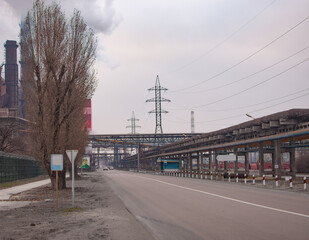 A road on a large industrial site. Pipelines, power lines, smoking pipes.