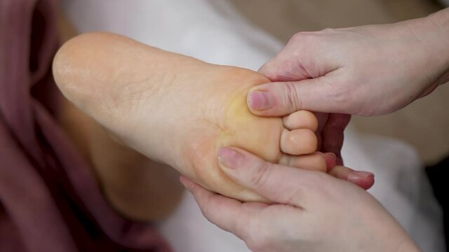 Female hands professionally massage the foot and toes. Woman massage therapist doing relaxing feet massage close up