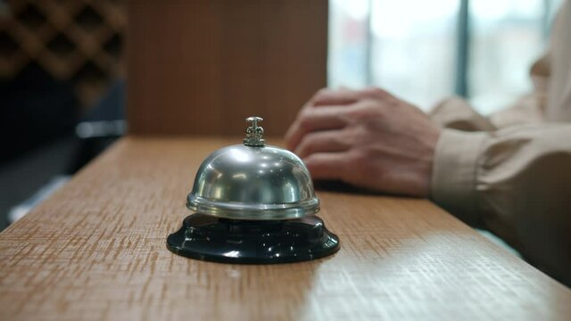 Close-up of female hand ringing reception desk bell then taking key card during check-in in hotel lobby. Travelling and accommodation concept.