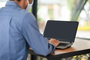 Asian businessman wear facemask working laptop computer in office