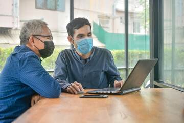 Two Asian man meeting business by laptop computer in cafe, Two people wear face mask prevent coronavirus covid19
