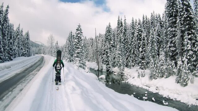Man Touring Pristine Snow Covered Mountains with Highway and River