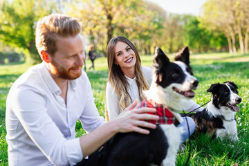 Naklejka na ściany i meble Young couple in love walking and enjoy time in park with dogs