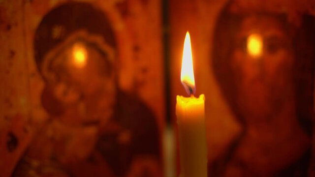 A church candle burns against the background of the icon, the Mother of God and Jesus Christ.