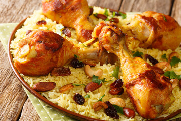 Arabic Chicken Majboos which is a spiced rice and chicken topped with nuts, raisins closeup in the plate. horizontal