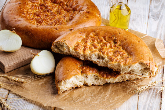 Broken fresh baked onion flat bread on the wooden background