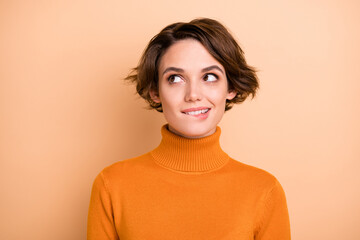 Portrait of young attractive lovely happy positive cheerful smiling girl bite lips look copyspace isolated on beige color background