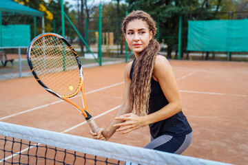 Confident handling of the ball when playing on the net. An attractive, beautiful tennis player practicing exercises to improve her skill level. Games in motion, action. Favorite sport - tennis