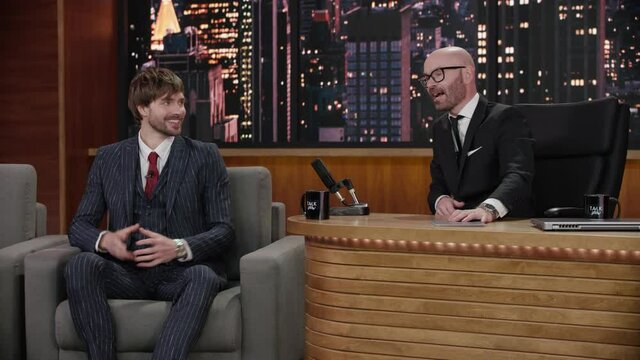 FIXED Late-night talk show host showing a green board with tracking points to celebrity guest in a studio. TV broadcast style show. Shot with RED cinema camera