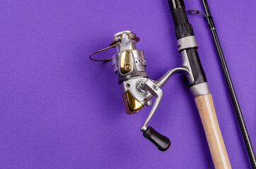 Fishing rod with attached fly fishing reel on blue background.