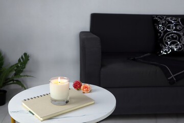 Fototapeta na wymiar luxury aroma lighting aromatic scented candle glass displayed on white marble table to creat romantic and relax ambient on valentine day with background of grey sofa in living room