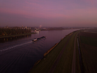 Barge boat cruising on the Ghent-Terneuzen canal, towards Terneuzen, at dawn. Aerial view 