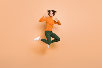 Fototapeta na wymiar Full size photo of young happy excited positive cheerful girl jumping showing thumb-up isolated on beige color background
