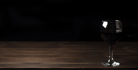 Glasses of red wine on a wooden table. Against the background of darkness