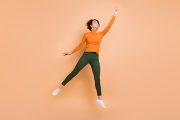 Fototapeta na wymiar Full size photo of young beautiful happy positive smiling cheerful girl jump look copyspace isolated on beige color background