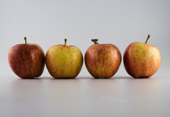 Four red and yellow apples in line isolated on white