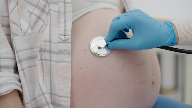 Female doctor listening to fetal heart rate, examining belly in hospital, health
