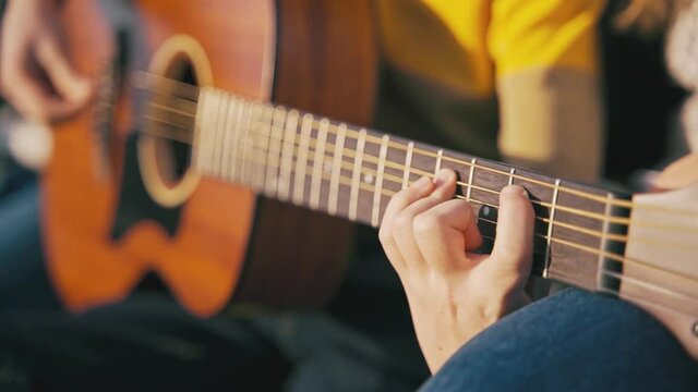 Slow-motion cinematic close-up shot of kid's hands playing chords on the guitar.