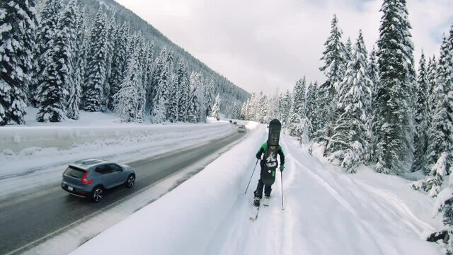 Roadside Splitboard Hiking in Snowy Mountains with Cars Passing