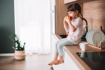 Cute little girl eating tasty red apple