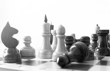 close-up chess pieces on a chessboard during the game in black and white