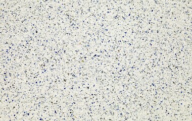White concrete wall with colored glass fragments and white pebbles inserted into the surface. Detail, background and texture 