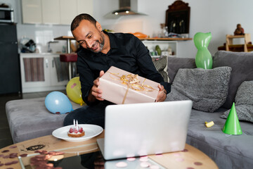 Virus pandemic and social impact: 40 years old man celebrating his birthday at home using his computer to talk to his family