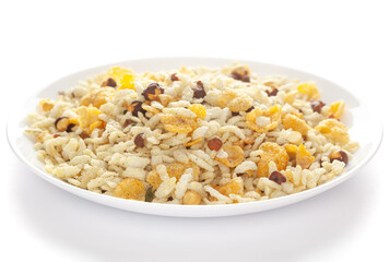 Crunchy Diet Lite Mixture in a white ceramic plate made with Puffed Rice, Corn Flakes, and Curry leaves. Pile of Indian spicy snacks (Namkeen), under backlight, side view, 
