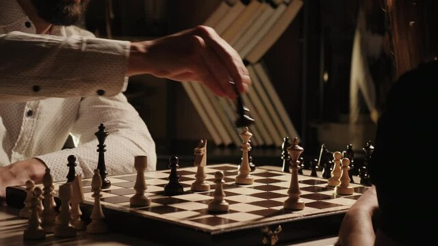 Young adult man and woman playing chess indoors, shaking hands expressing victory or offering a draw