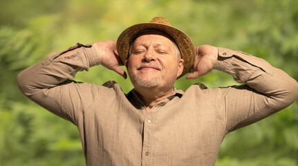 Ein älterer Mann mit Hut sitzt im Sonnenlicht und freut sich seines Lebens. Der natürliche...