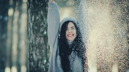 Emotional photo of a young woman. Beautiful woman throws snow and have fun in the winter snowy forest.