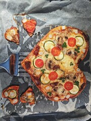 Cooking a pizza heart for the Valentine's Day holiday. Flat lay of classic Italian pizza with cherry, mushrooms and mozzarella. 