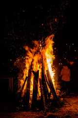 Novi Sad, Serbia - January 06, 2021: Orthodox Christianity custom during Christmas eve. Fire of fire, burning logs of firewood. Sparks bounce off from a bonfire at night.
