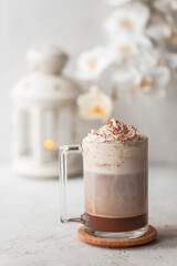Hot latte macchiato with delicious foam in a tall transparent glass on an easy table setting. Photo in a high key. Breakfast time. Rustic background.