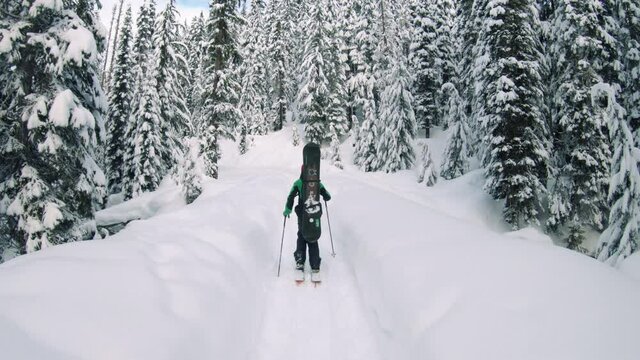 Snowy Mountain Hiking Adventure Following Man with Skis and Poles