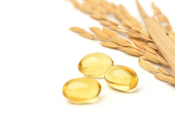 Close-up Rice bran and germ oil capsules with paddy ears rice on white background.