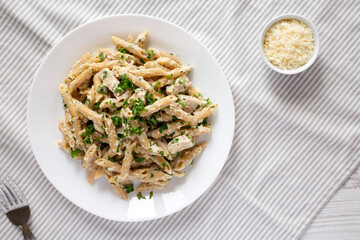 Homemade Chicken Alfredo Penne with Parsley on cloth, top view. Overhead, from above, flat lay.
