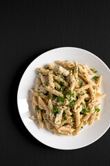 Homemade Chicken Alfredo Penne with Parsley on a black surface, top view. Overhead, from above, flat lay. Copy space.
