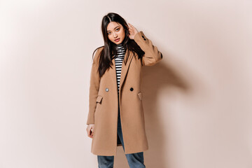 Beautiful Asian woman looking confidently into camera. Girl in beige coat posing on isolated...