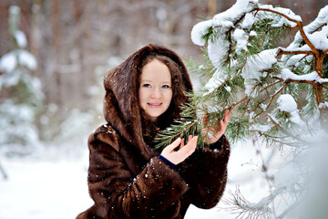 Portrait of a young girl in a fur coat on a Sunny winter day in the Park. The girl looks tenderly...