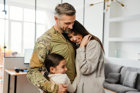 Happy Masculine Military Man Smiling And Hugging His Family Indoors